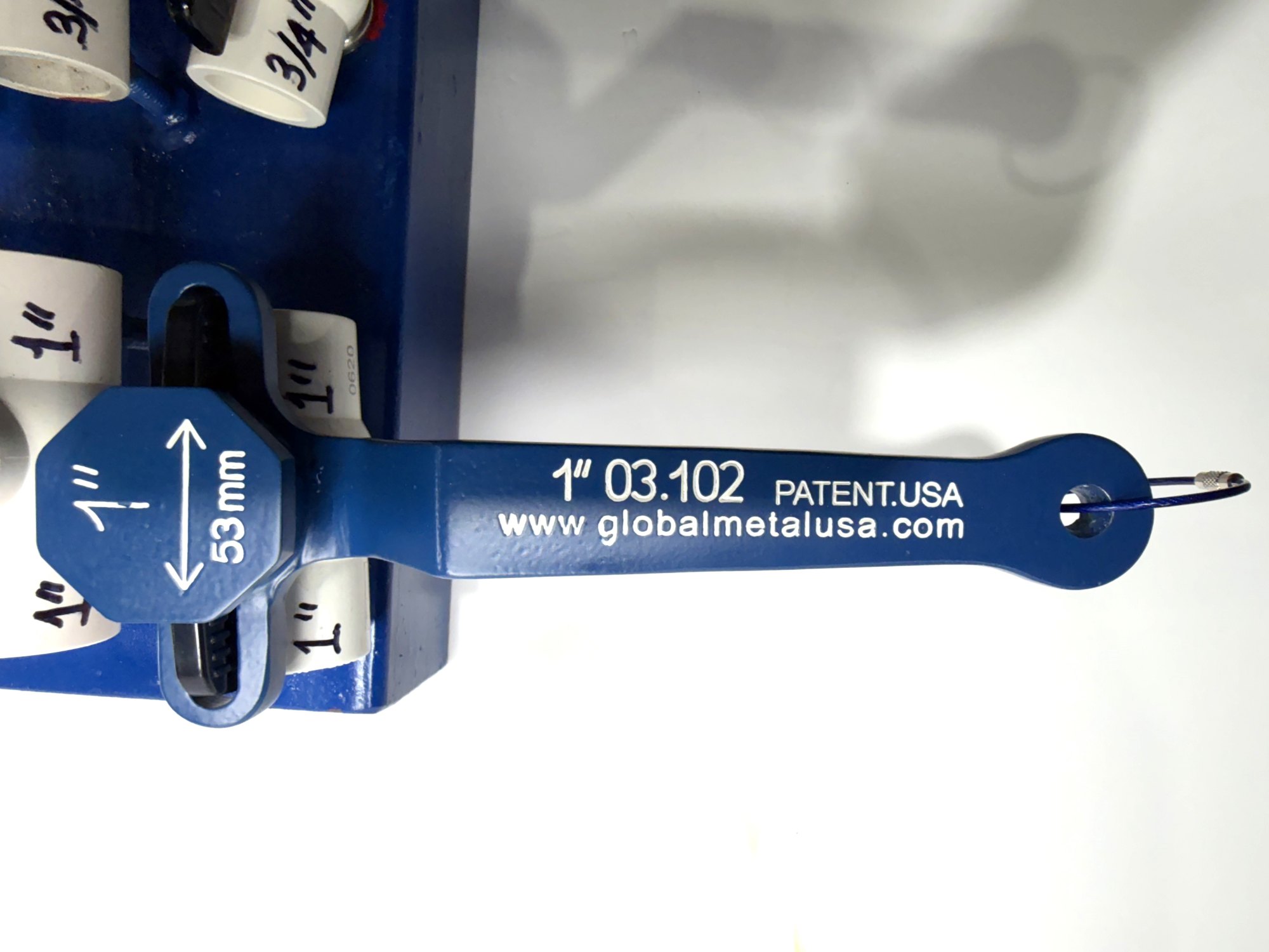 1-inch PVC ball valve frame wrench fitted on the black-handled 1-inch valve, its ribbed handle seen through the slots, item 03-102
