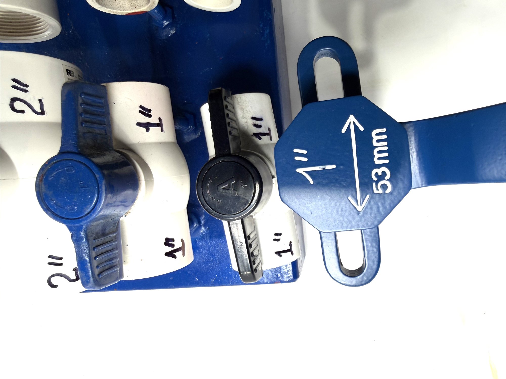 1-inch PVC ball valve frame wrench head beside 1-inch PVC valves with blue and black lever handles on a board, item 03-102