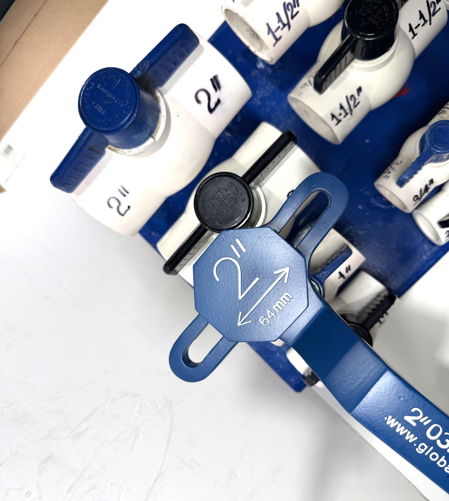 2-inch PVC ball valve frame wrench head, angled close-up on a PVC valve display board beside marked 2" valves, item 03-104