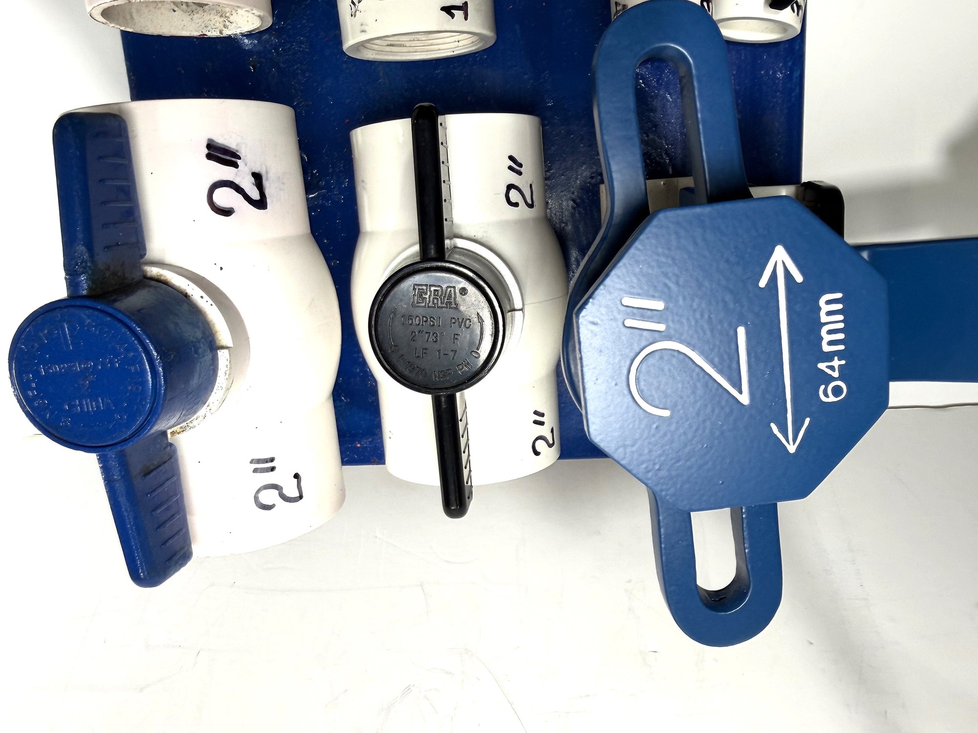 2-inch PVC ball valve frame wrench head on a display board beside 2" blue-handle and black-handle PVC valves, item 03-104