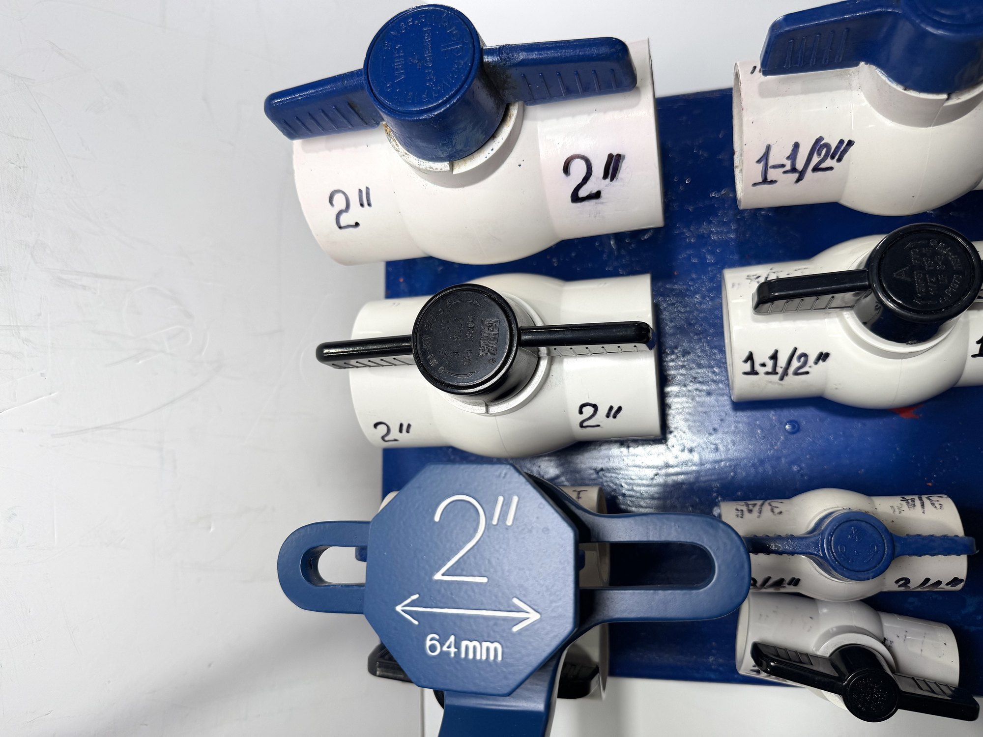 2-inch PVC ball valve frame wrench head seen face-on on a display board, marked 2" PVC ball valves above it, item 03-104